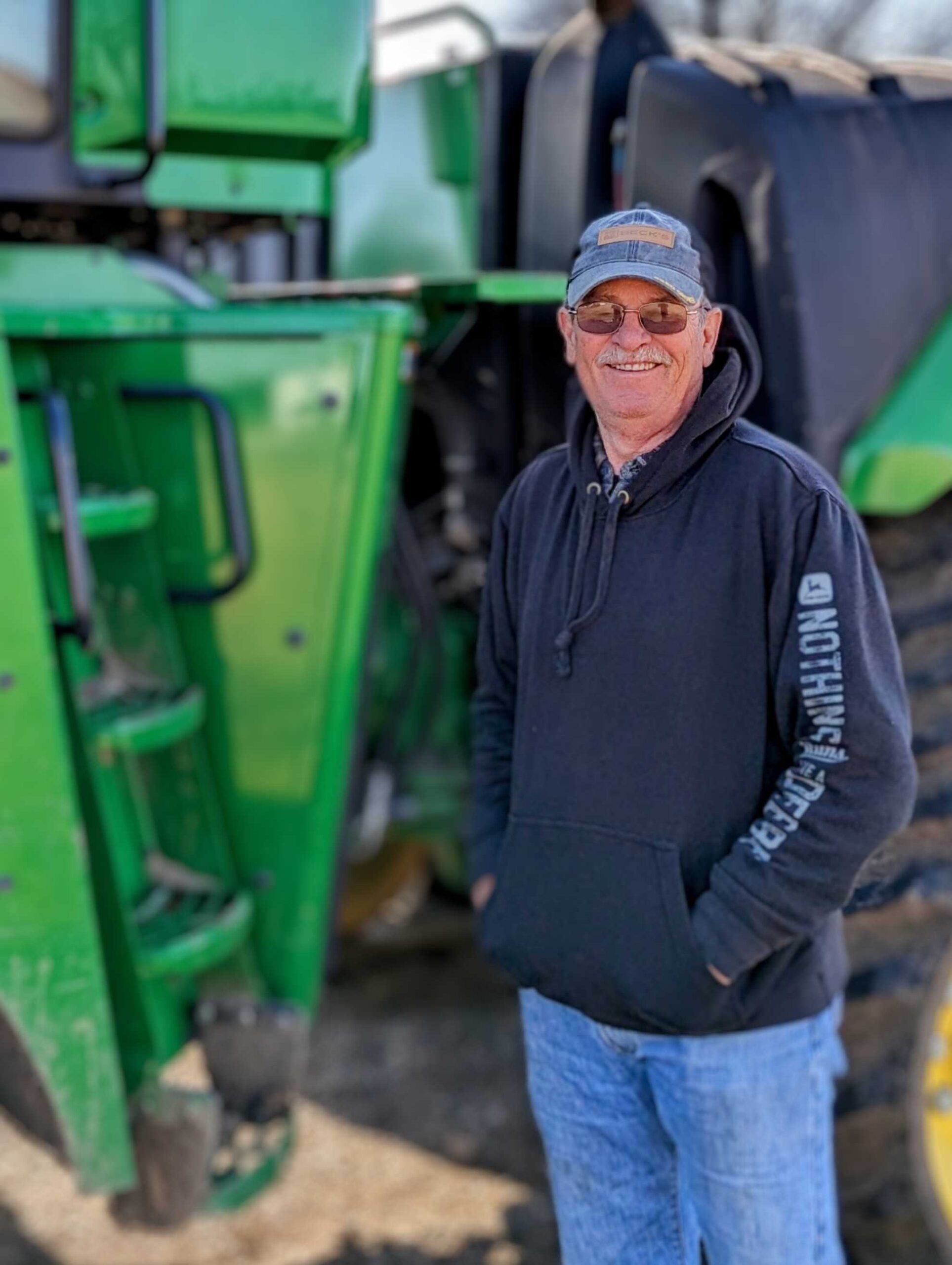 Mike Adams standing beside a green tractor