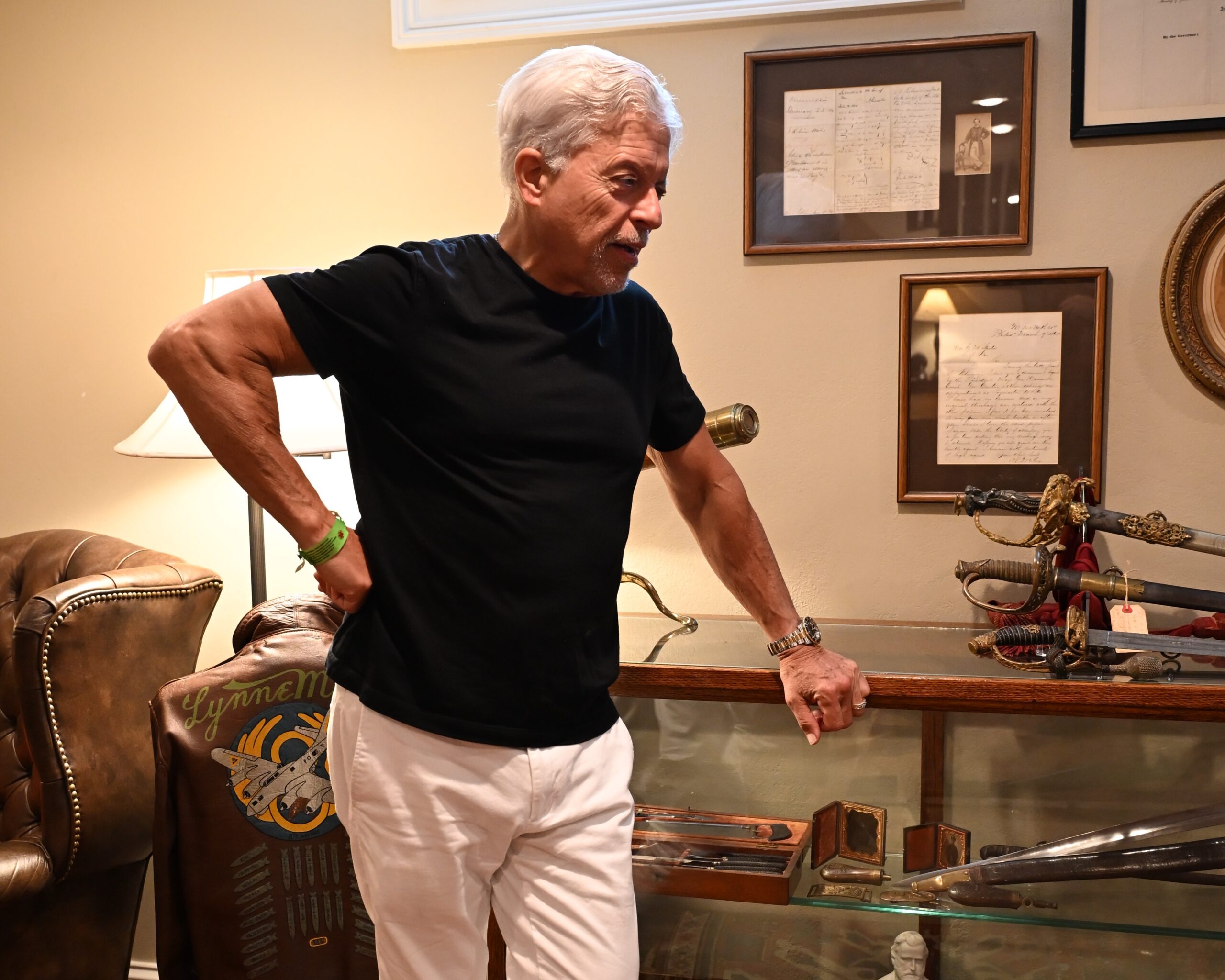 Bill Given leaning on a glass display case of swords and sabers