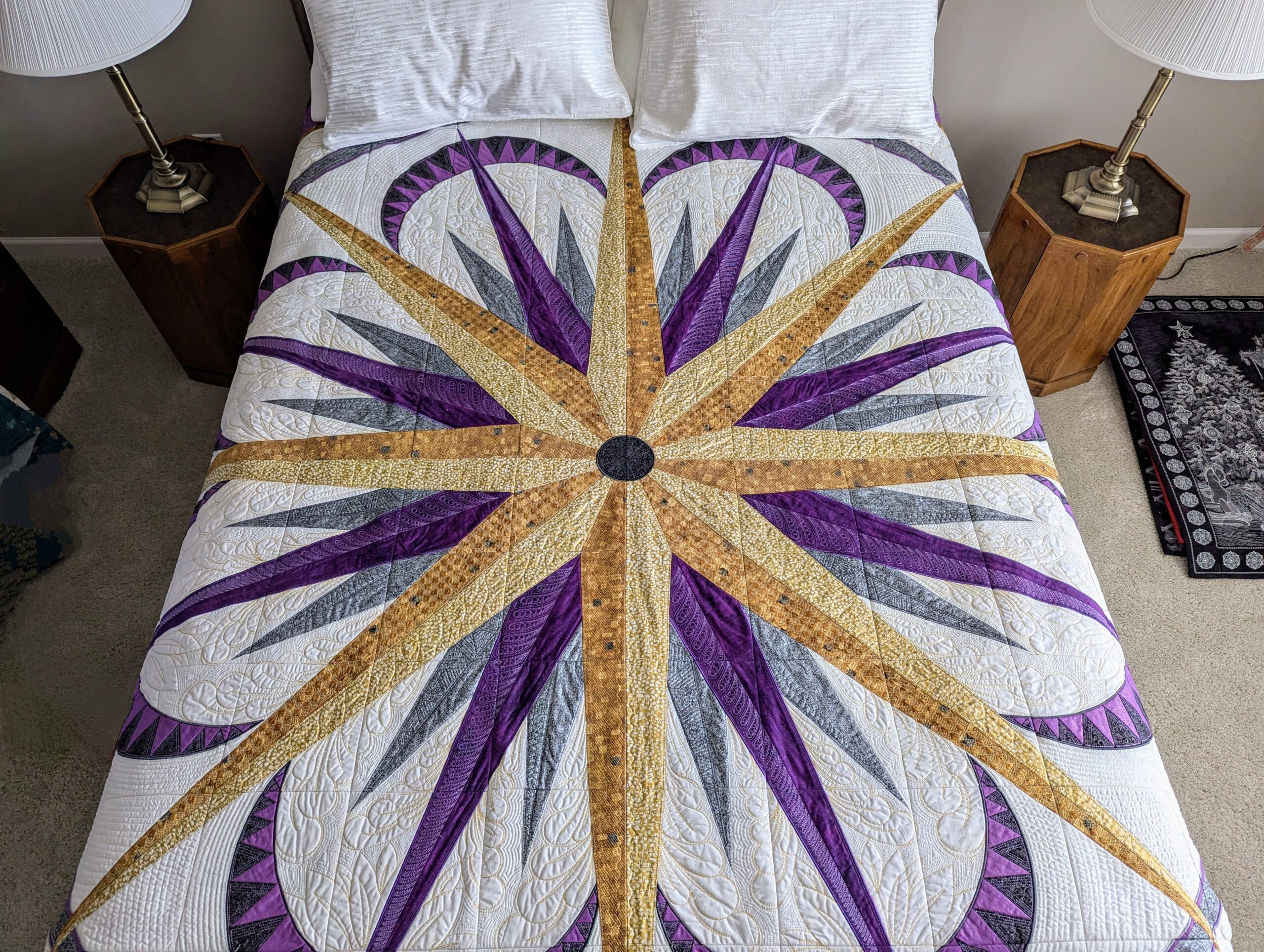 A purple and gold compass-star quilt spread across a bed