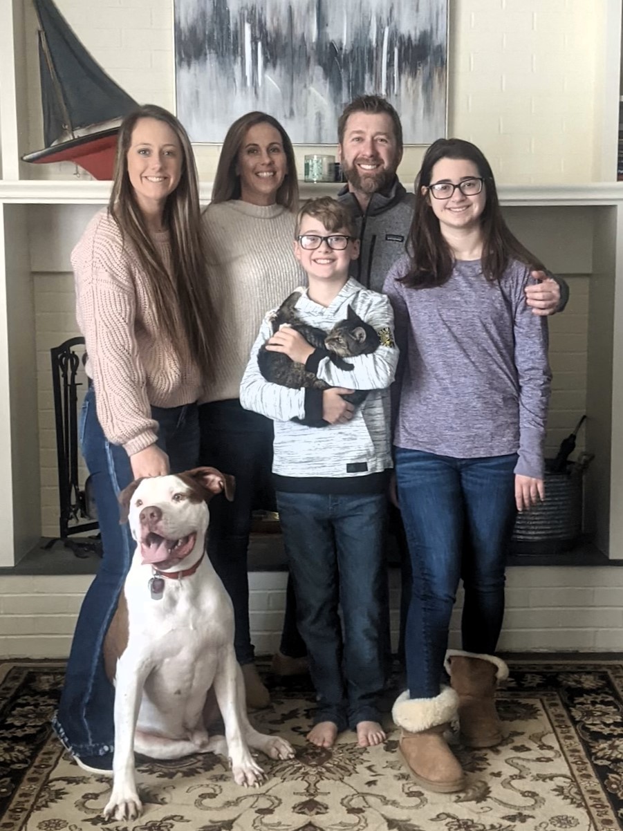 Eric, Angel, and their children posing at home with their dog and cat